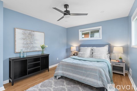 A bedroom with a bed, nightstand, and a painting on the wall.