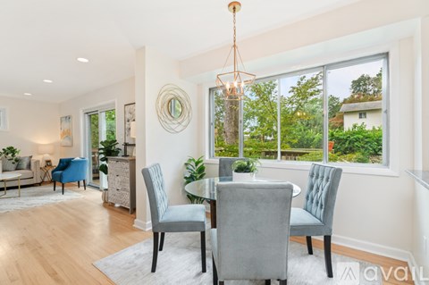 A dining room with a table set for two and a view of a garden outside the window.