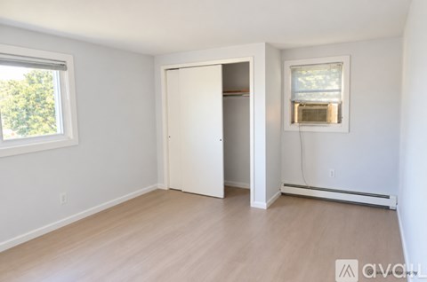 A room with a white door and a window with a view of trees outside.