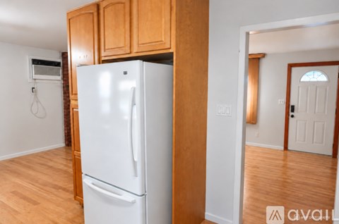 A white refrigerator in a kitchen with wooden cabinets.