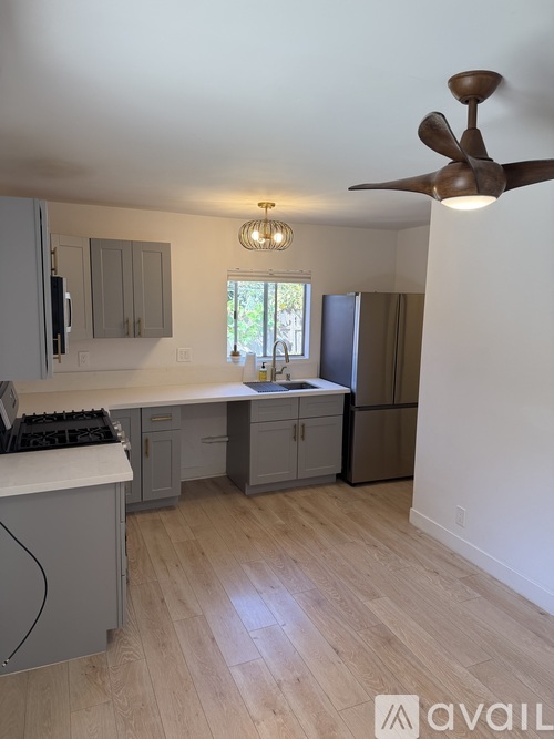 A kitchen with a fan and wooden floors.