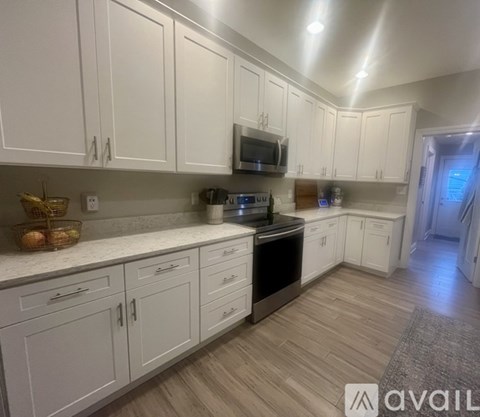 A kitchen with white cabinets and a wooden floor.