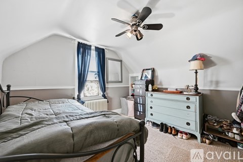 A bedroom with a bed, dresser, and a ceiling fan.