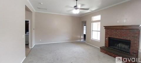 A living room with a fireplace and a ceiling fan.