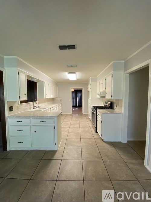 A kitchen with white cabinets and a tiled floor.