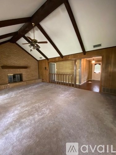 A spacious room with a brick fireplace and a ceiling fan.