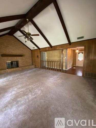 A spacious room with a brick fireplace and a ceiling fan.