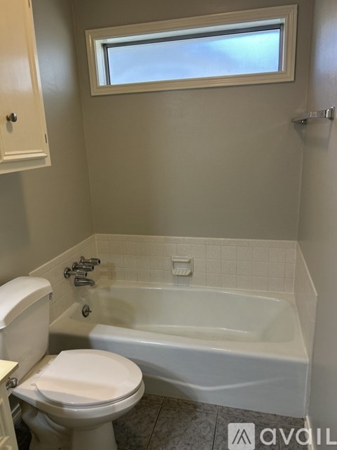 A white toilet sits next to a bathtub in a bathroom.