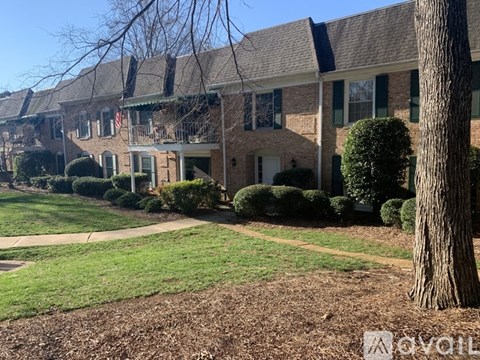 A tree stands in front of a house with a green lawn.