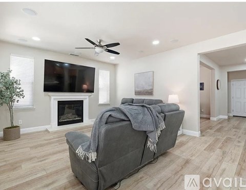 A living room with a grey couch and a fireplace.