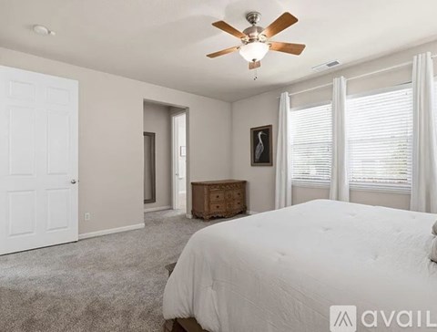 A bedroom with a white bed and a ceiling fan.