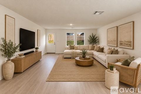 A living room with a white couch, a wooden coffee table, and a flat-screen TV.