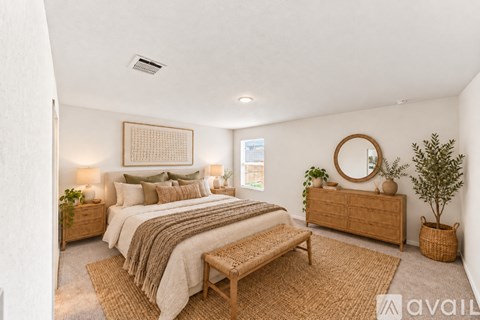 A bedroom with a large bed, a bench, and a mirror on the wall.