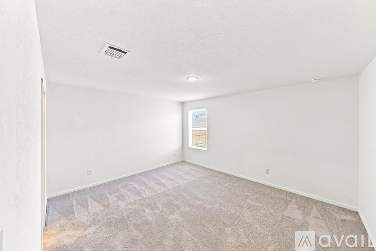 A room with a carpeted floor and a window showing a building outside.