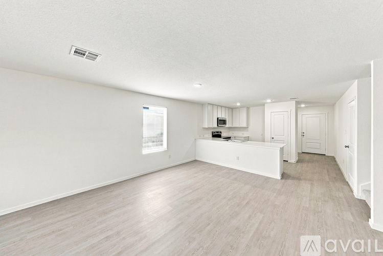 A spacious room with light wood flooring and white walls.