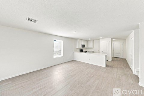 A spacious room with light wood flooring and white walls.
