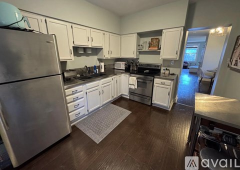 A kitchen with white cabinets and a stainless steel refrigerator.