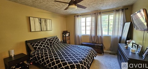 A bedroom with a bed, nightstand, and window with curtains.