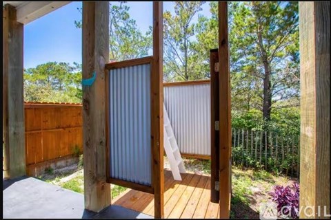 A wooden deck with a screen door open to a backyard.