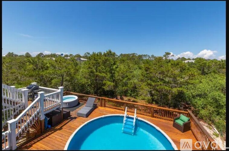 A wooden deck with a blue pool and white railings.