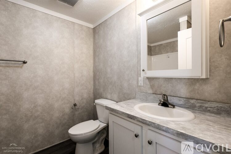 A bathroom with a toilet, sink, and mirror.