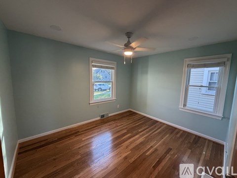 A room with wooden floors and two windows.