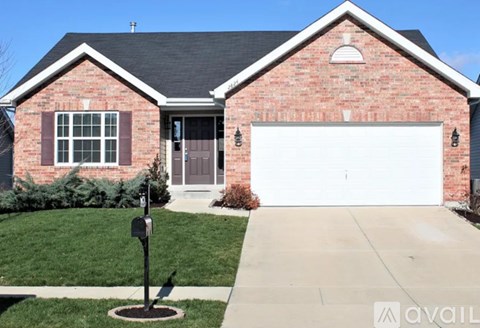 A red brick house with a white garage door and a mailbox on the sidewalk.