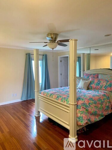 A bedroom with a four poster bed and a ceiling fan.
