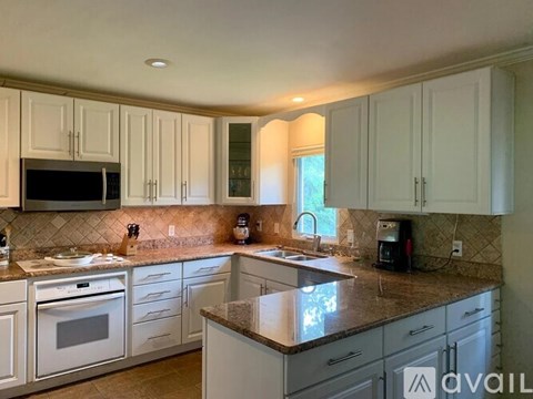 A kitchen with white cabinets and a granite countertop.