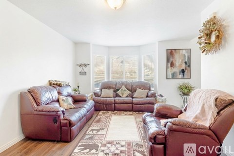 A living room with brown leather furniture and a rug.