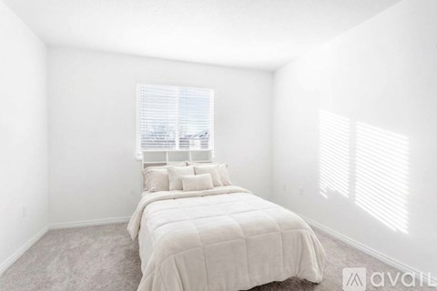A bedroom with a large bed and a window with blinds.