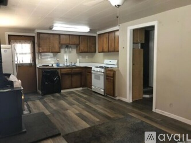A kitchen with wooden cabinets and a black trash bag.