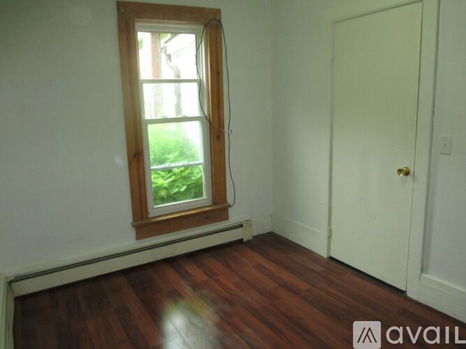 A room with a wooden floor, a window, and a door.