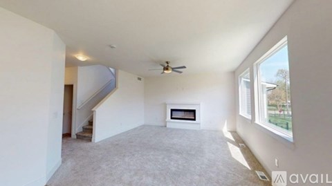 A spacious living room with a fireplace and a ceiling fan.