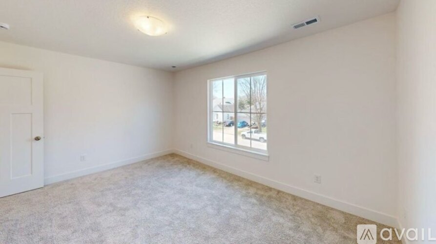 A spacious room with a carpeted floor and a window.