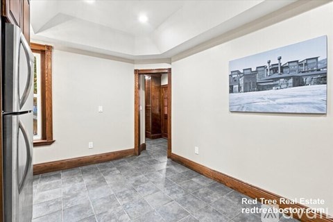 A spacious room with a tiled floor and a painting of a snowy landscape on the wall.