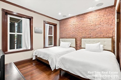 A bedroom with two beds and a wooden floor.