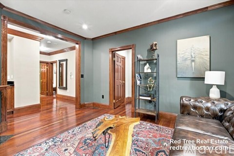 A living room with a brown leather couch and a rug.