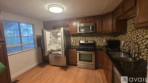 A kitchen with a refrigerator, stove, and microwave.