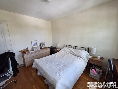A bedroom with a bed, nightstand, and chair.