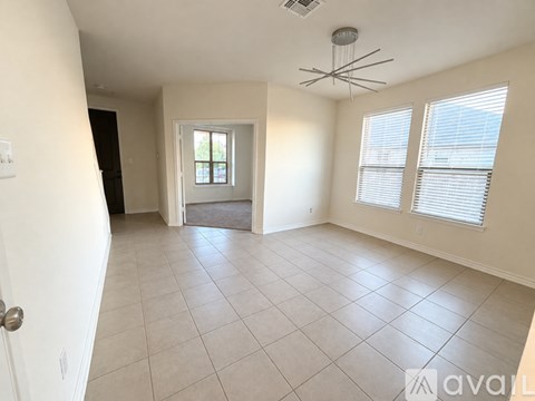A spacious room with tiled flooring and a ceiling fan.