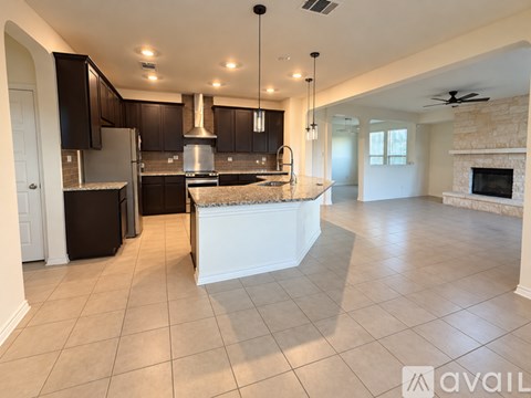 A spacious kitchen with a central island and a fireplace in the living room.