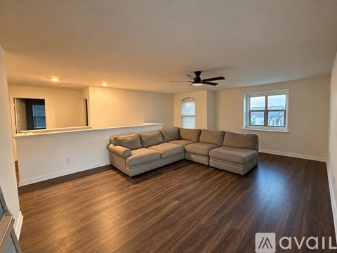 A living room with a large sectional sofa and a ceiling fan.