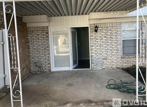 A patio area with a white railing and a door leading to a dark interior.