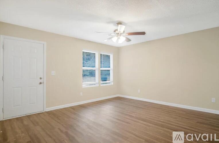 A room with a white door, a window with blinds, and a ceiling fan.