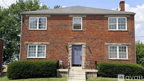 A red brick house with a grey roof and a blue door.