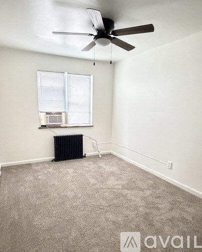 A room with a ceiling fan and a window with blinds.