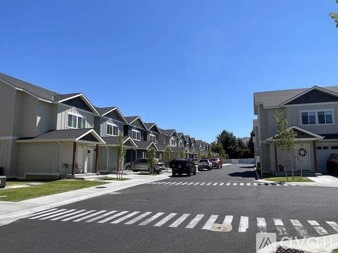 A row of houses with cars parked in front.