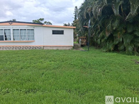 A house with a white and orange exterior is surrounded by a green lawn.