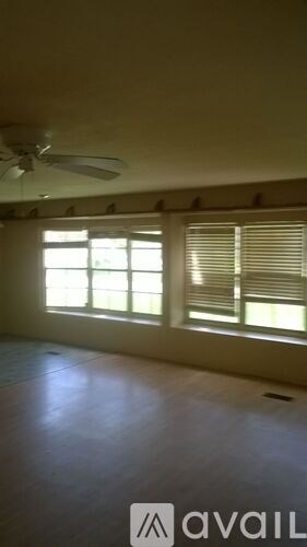 A room with a ceiling fan and a window with blinds.